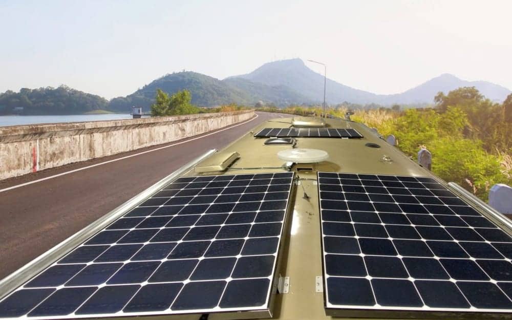 Motorhome roof covered in solar panels on a lakeside road